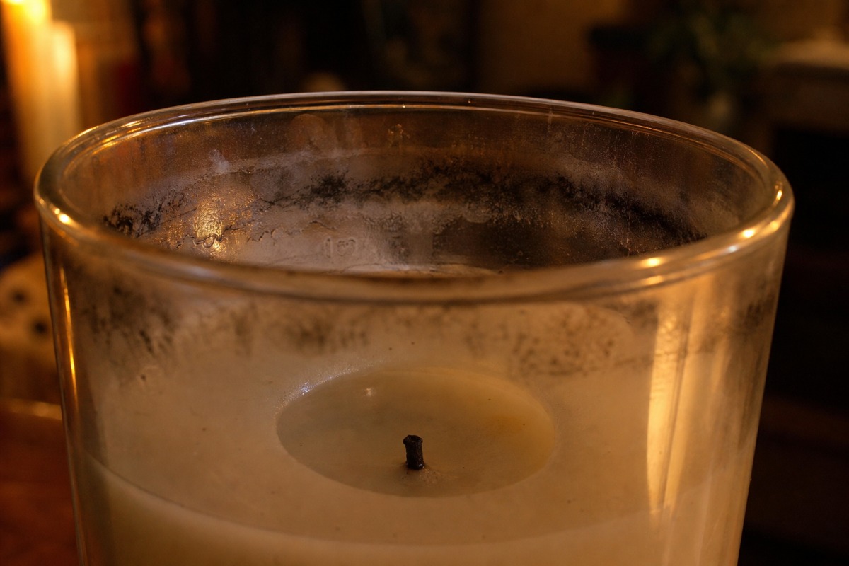 Parede interior de uma vela de vidro com riscas negras e gordurosas de fuligem no terço superior