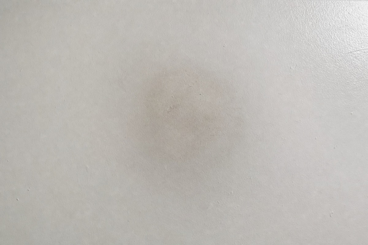 Suave sombra cinzenta de fuligem no teto branco, por cima do lugar onde estava uma vela de parafina